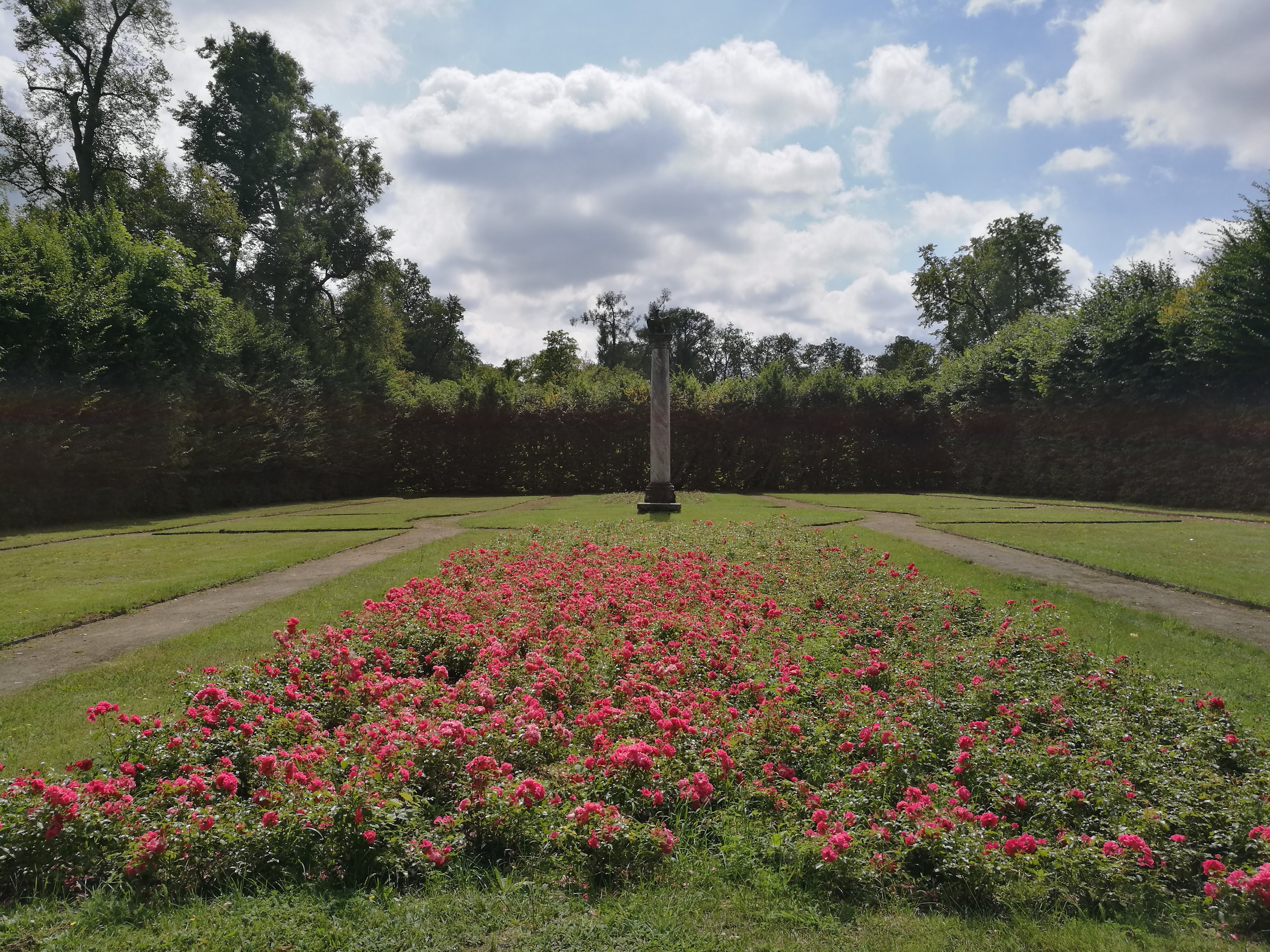 Red flowers lead to a grey, concrete column.